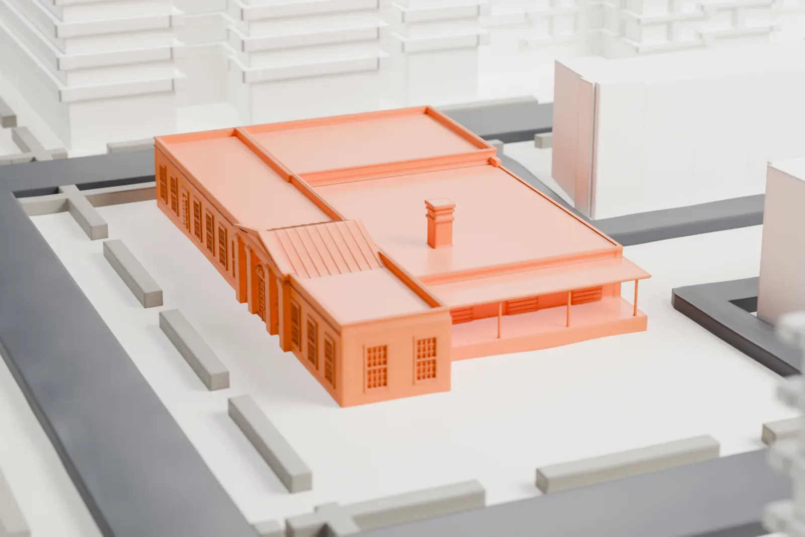 A white 3D print of the Jackson Heights post office, a low, wide building with a pedimented entrance, set among street blocks and larger neighboring buildings.