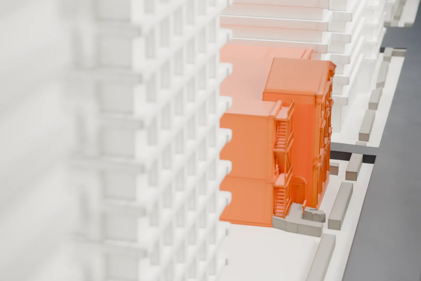 A white 3D print of the Lenox Hill post office, a low building set among dense blocks of tall buildings and narrow streets.