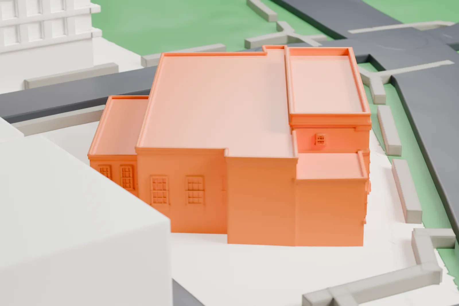 A white 3D print of the Scarsdale post office, a symmetrical brick building with a columned entrance and lower side wings, beside streets, lawns and larger buildings.