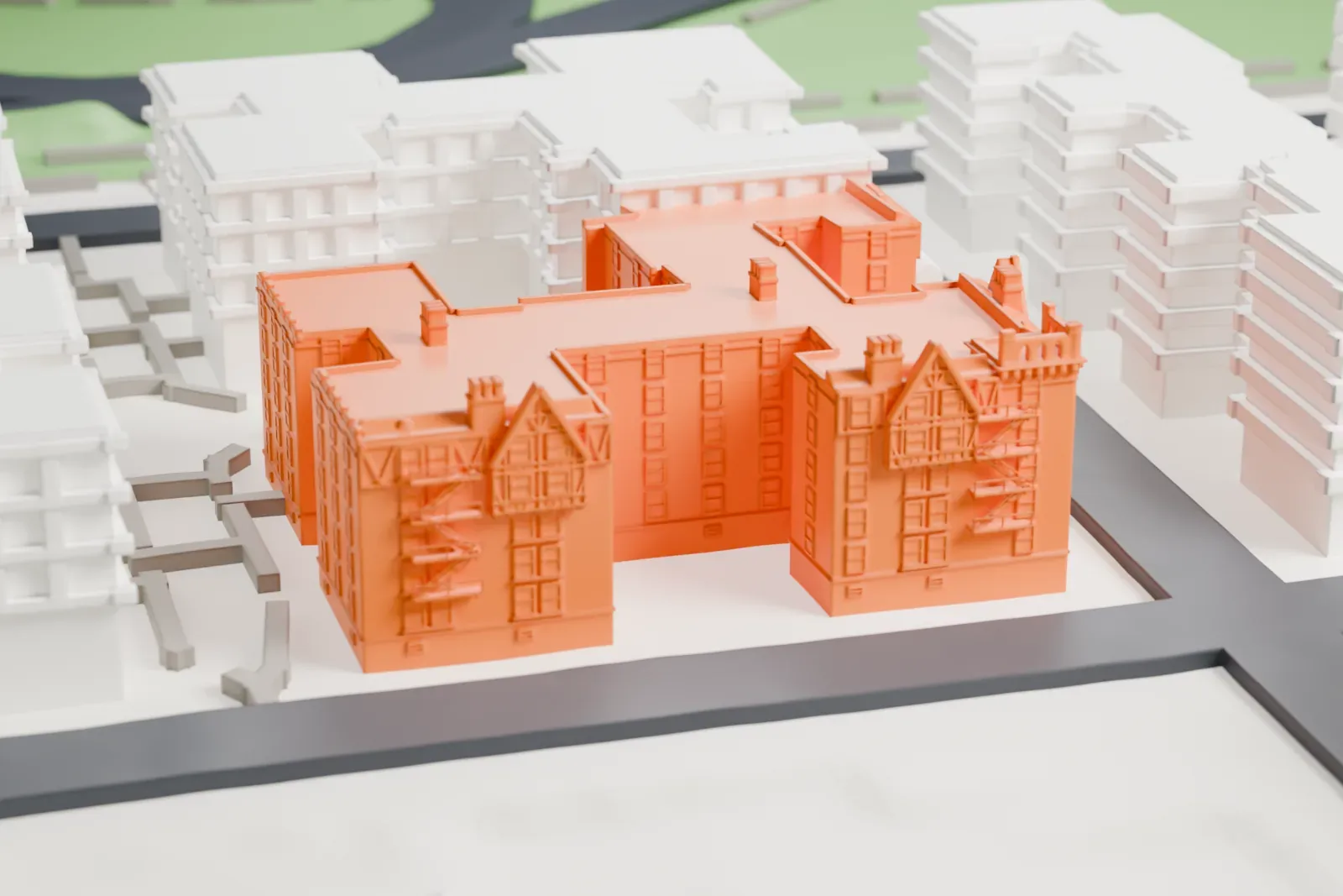 A white 3D print of United Workers Cooperatives, a long irregular block of buildings with gabled roofs, small towers and chimneys, set among streets and larger plain buildings.