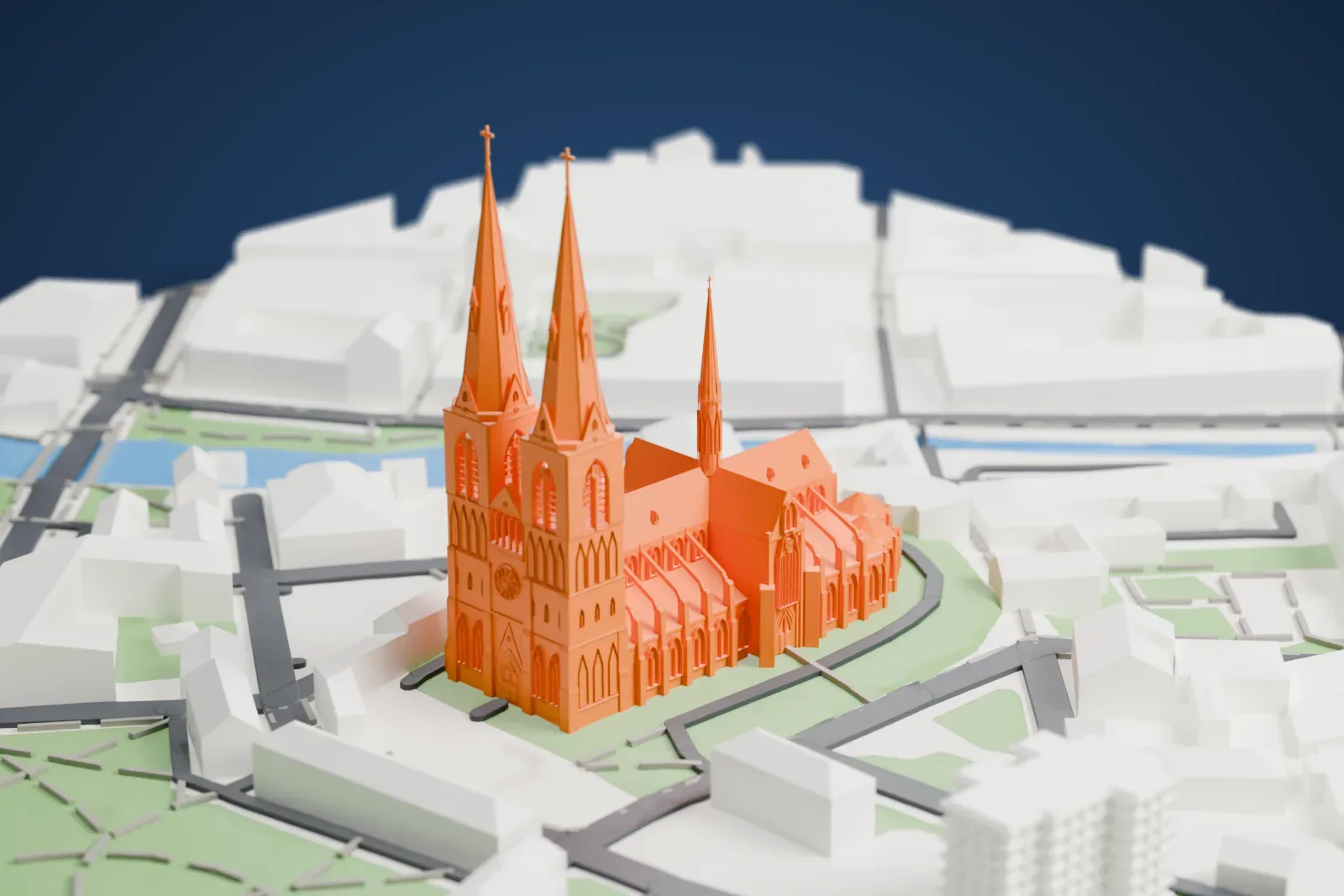 A white 3D print of Uppsala Cathedral, a Gothic church with two tall west spires and a slender spire over the crossing, set among low buildings, parkland and a river.