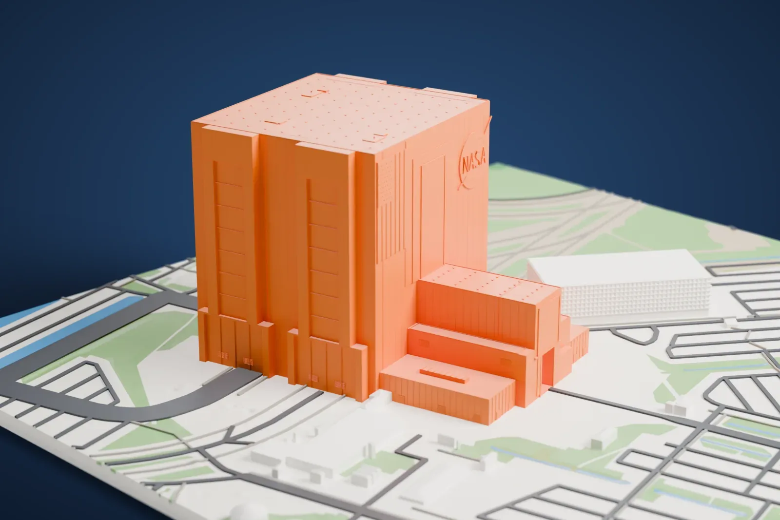 A white 3D print of the Vehicle Assembly Building, with its tall high bay and lower wing on the surrounding site.