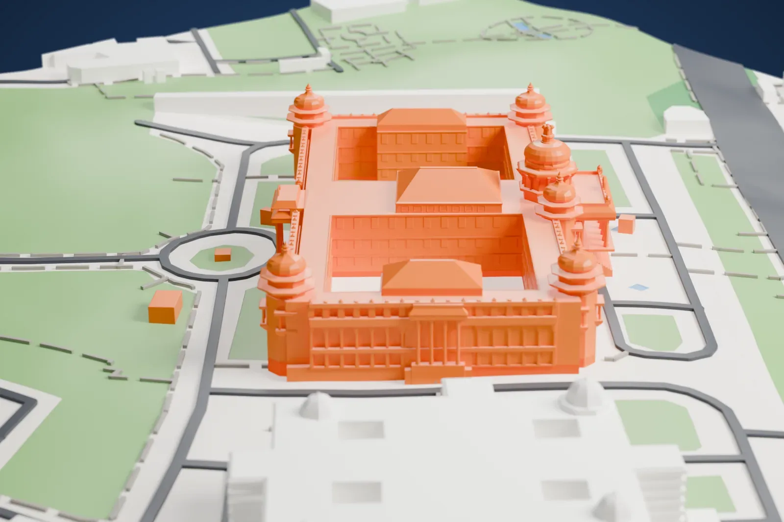 A white 3D print of Vidhana Soudha, a large rectangular government building with a central dome, corner cupolas and inner courtyards, set among green lawns, roads and neighboring buildings.
