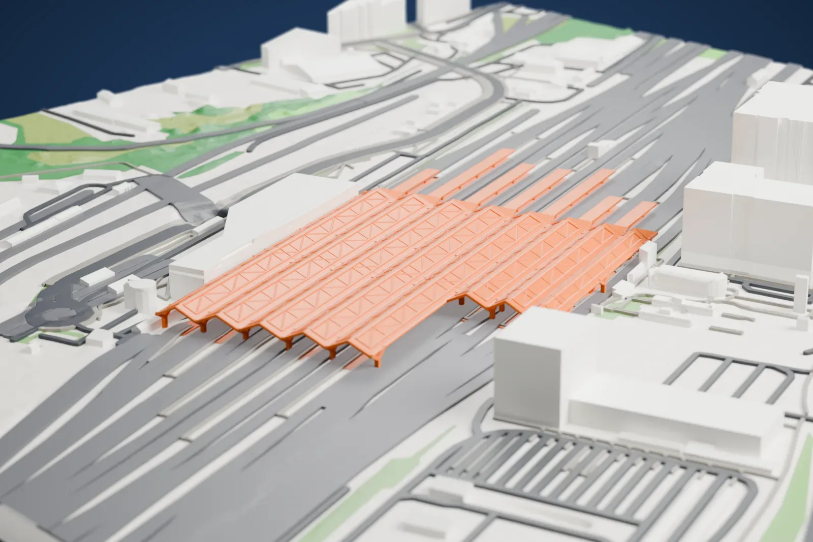 A white 3D print of Warszawa Zachodnia station, a long station with platform roofs, among the surrounding city buildings.
