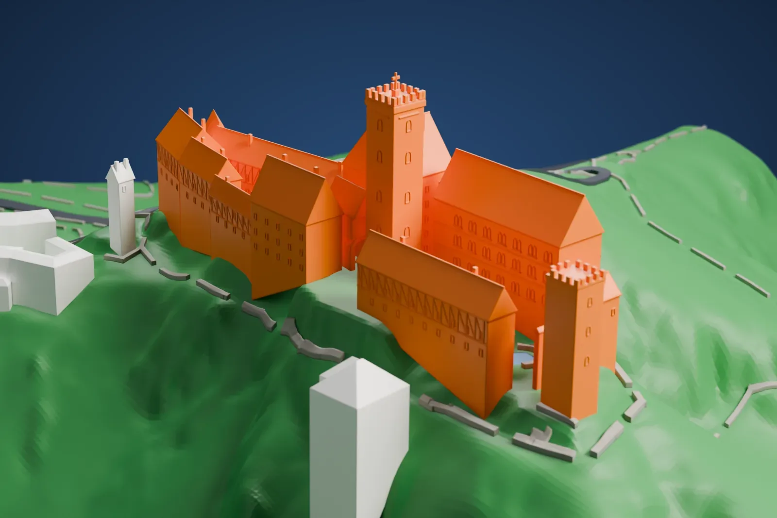 A white 3D print of Wartburg Castle, a cluster of long steep-roofed halls and two battlemented towers on a green hilltop, with a few buildings and roads on the slopes nearby.