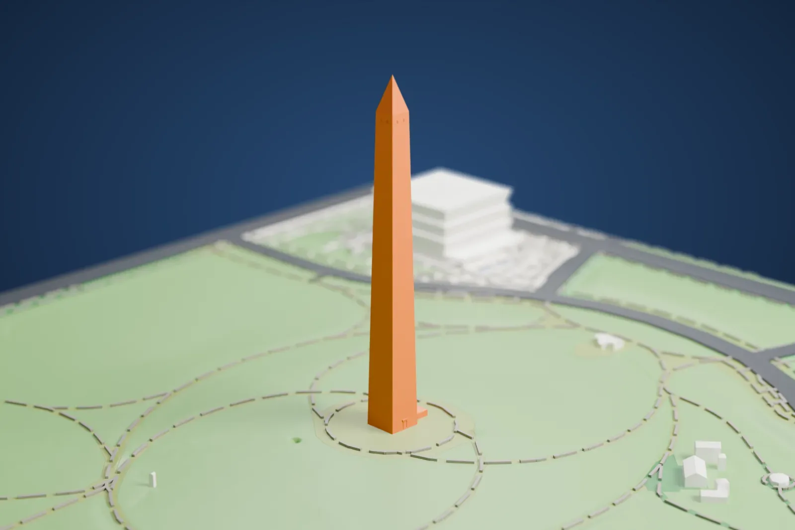 A white 3D print of the Washington Monument, a tall slender obelisk with a pointed top, standing on a green lawn crossed by curving paths.