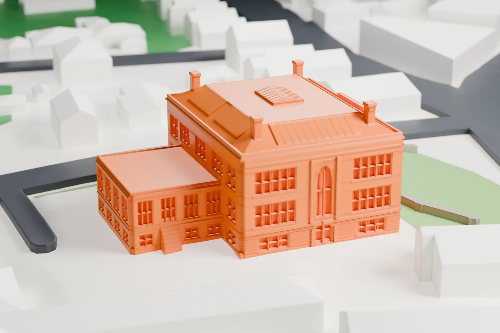 A white 3D print of the former Washington School, a large school with chimneys on its roof, on a lawn with paths, roads and houses nearby.
