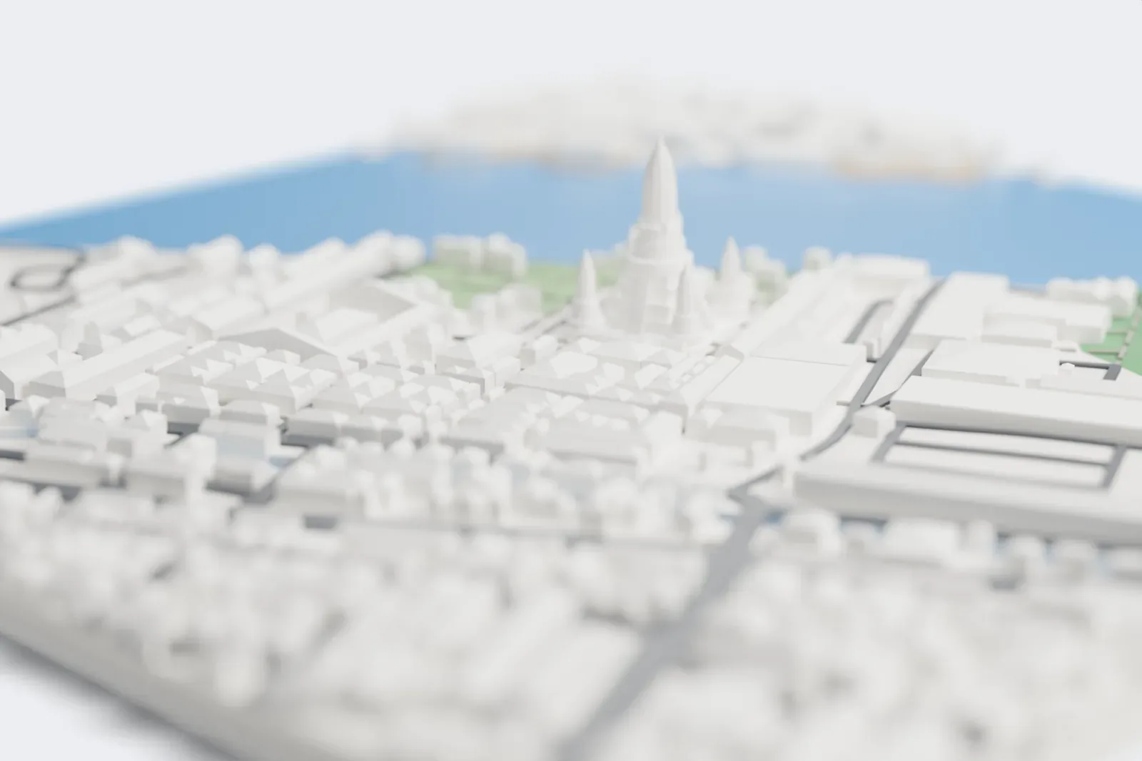 A white 3D print of Wat Arun, a tall tapering central prang with four smaller prang around it on stepped terraces, among low buildings beside a river.