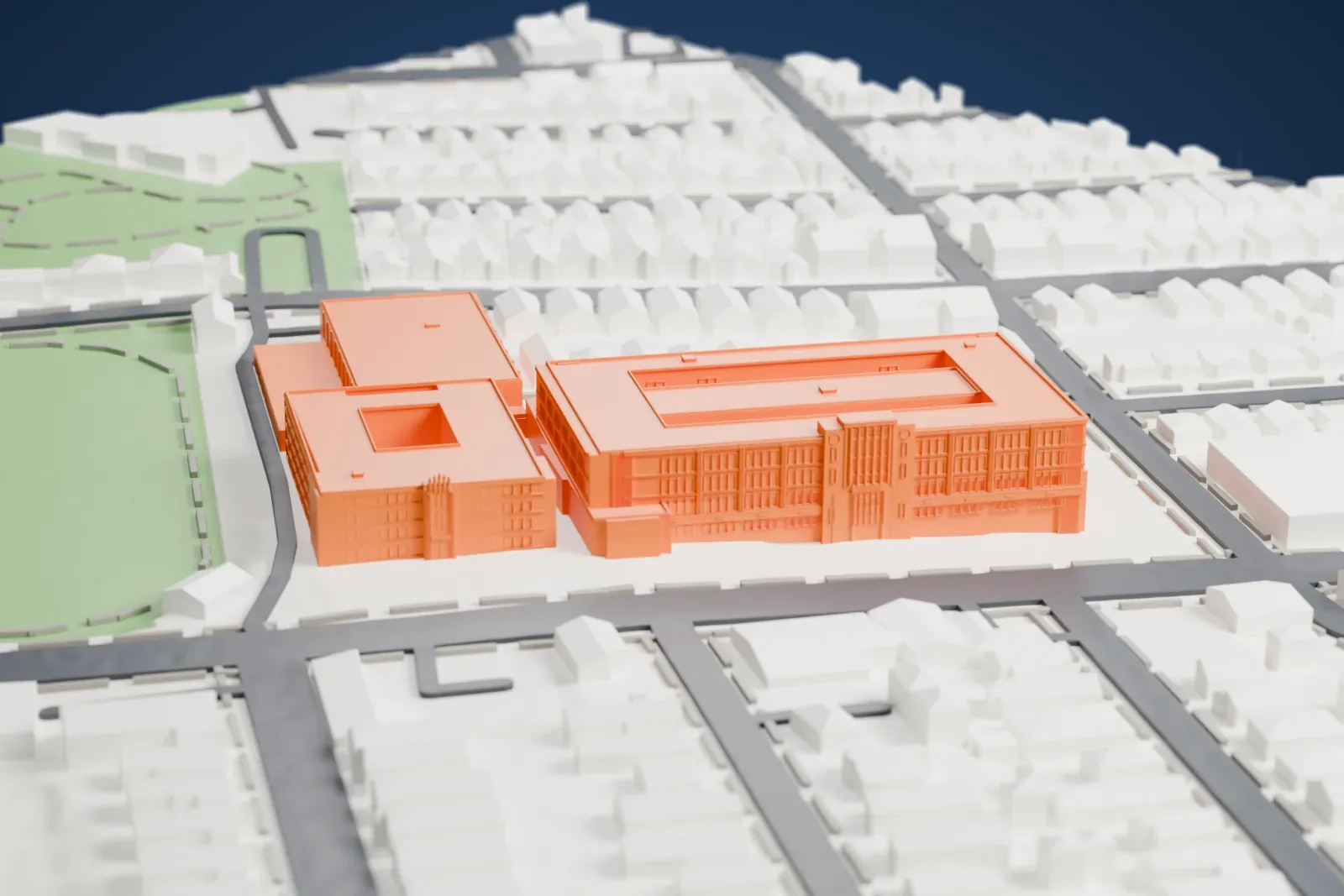 A white 3D print of Weequahic High School, a group of connected school wings with inner courtyards, beside an oval athletic field and blocks of small buildings.
