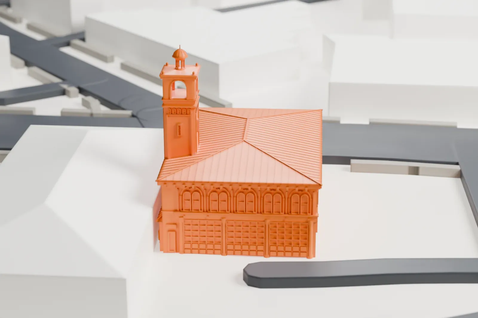 A white 3D print of the Westfield Fire Headquarters, a firehouse with a hipped roof and a bell tower, beside streets, a green lawn and larger buildings.