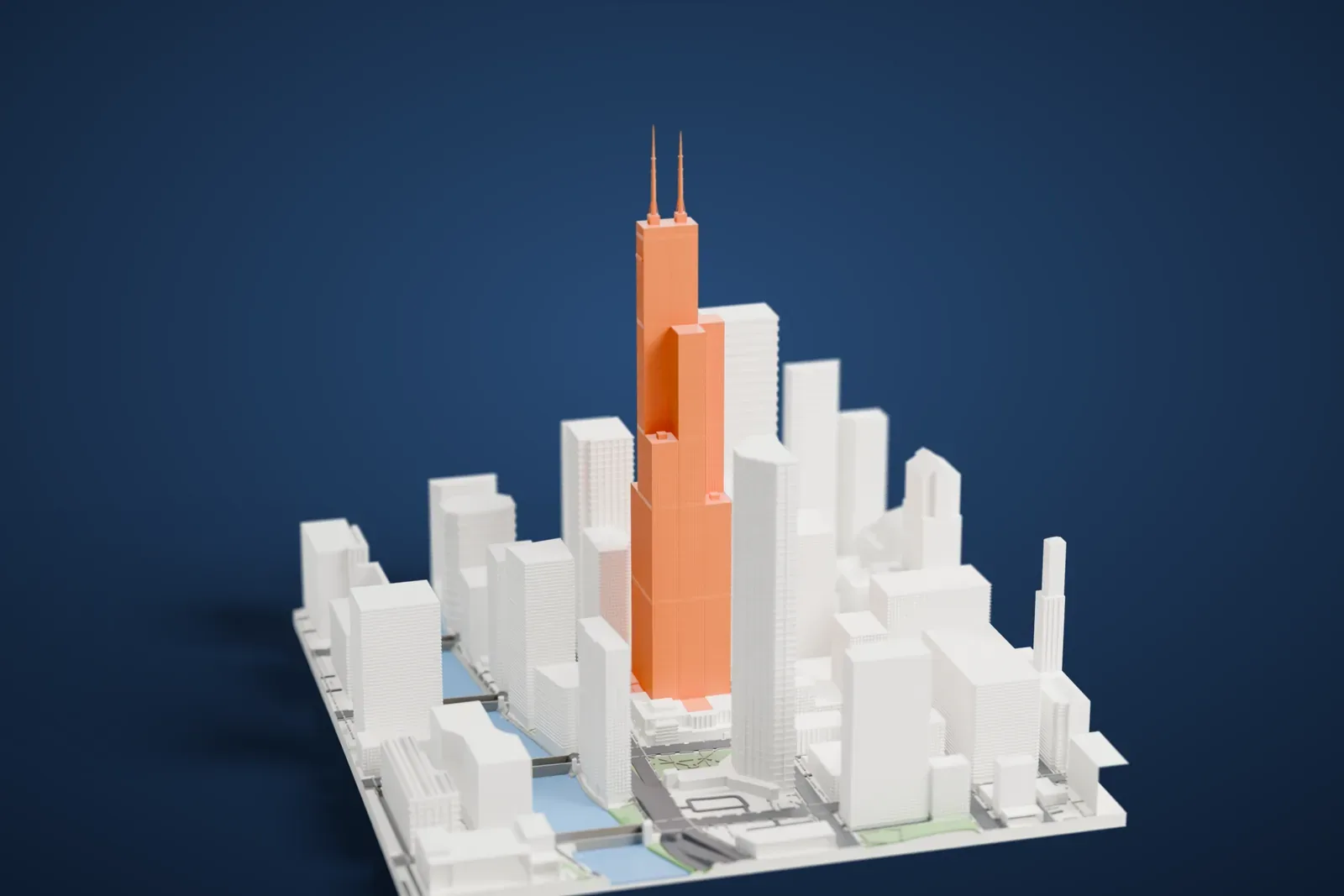 A white 3D print of the Willis Tower, a stepped tower with two antennas, rising above a dense grid of downtown Chicago skyscrapers with a stretch of water at the edge.