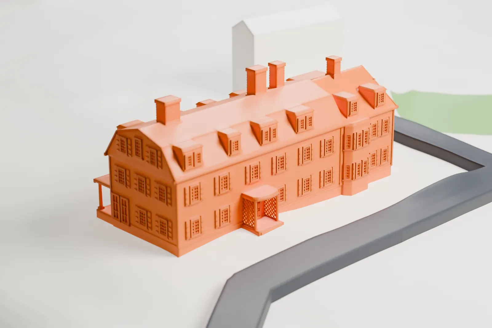 A white 3D print of Willowmere, a long mansion with a steep roof, several chimneys and a front porch, set on open ground beside roads.