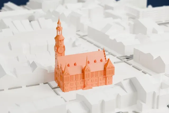 A white 3D print of the Wrocław Old Town Hall, a Gothic hall with stepped gables, small turrets and a tall clock tower, among tightly packed buildings.
