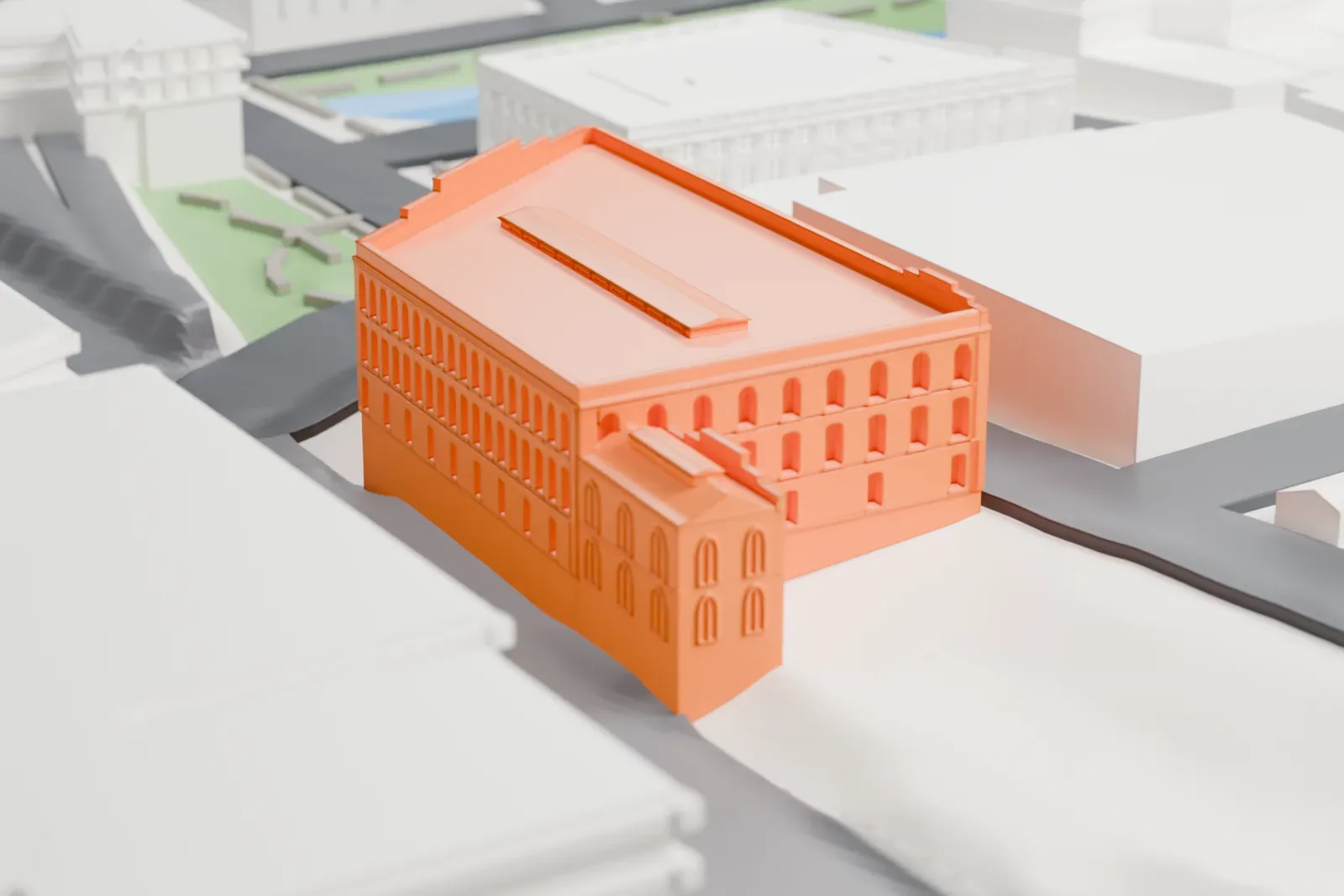 A white 3D print of the Yonkers Trolley Barn, a large three-story building with an angled corner and a long raised strip on its flat roof, among streets and taller buildings.
