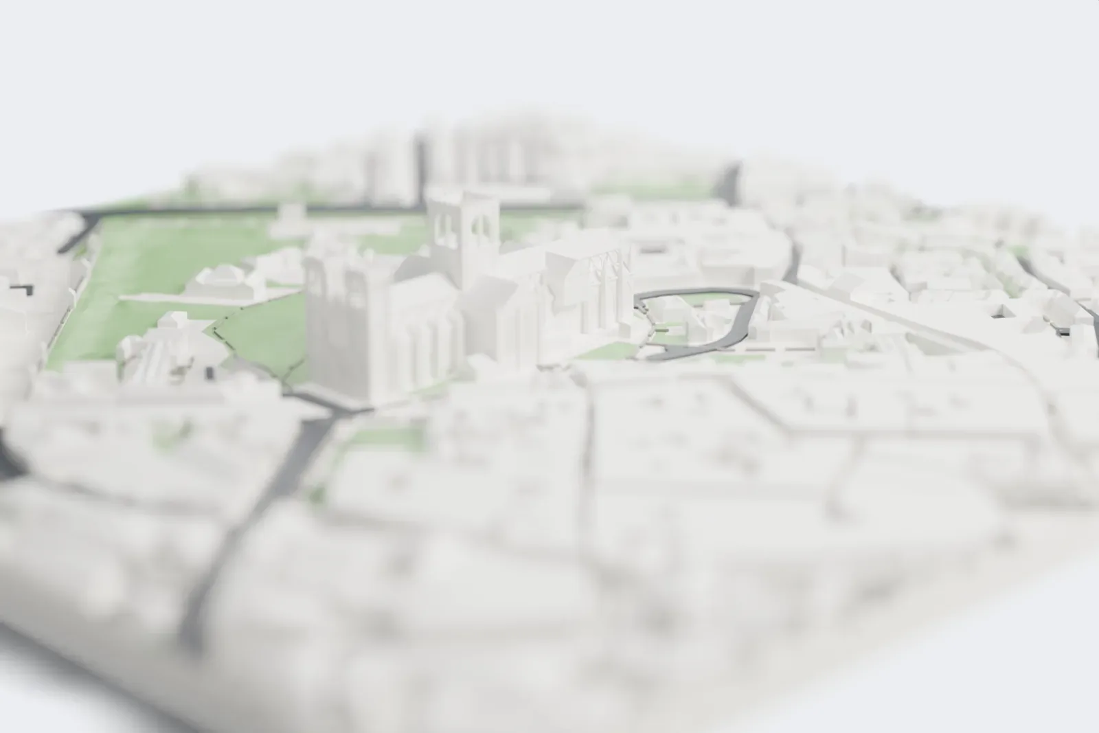 A white 3D print of York Minster, a long cross-shaped cathedral with a central tower and two western towers, standing among green lawns and paths with streets and buildings around it.