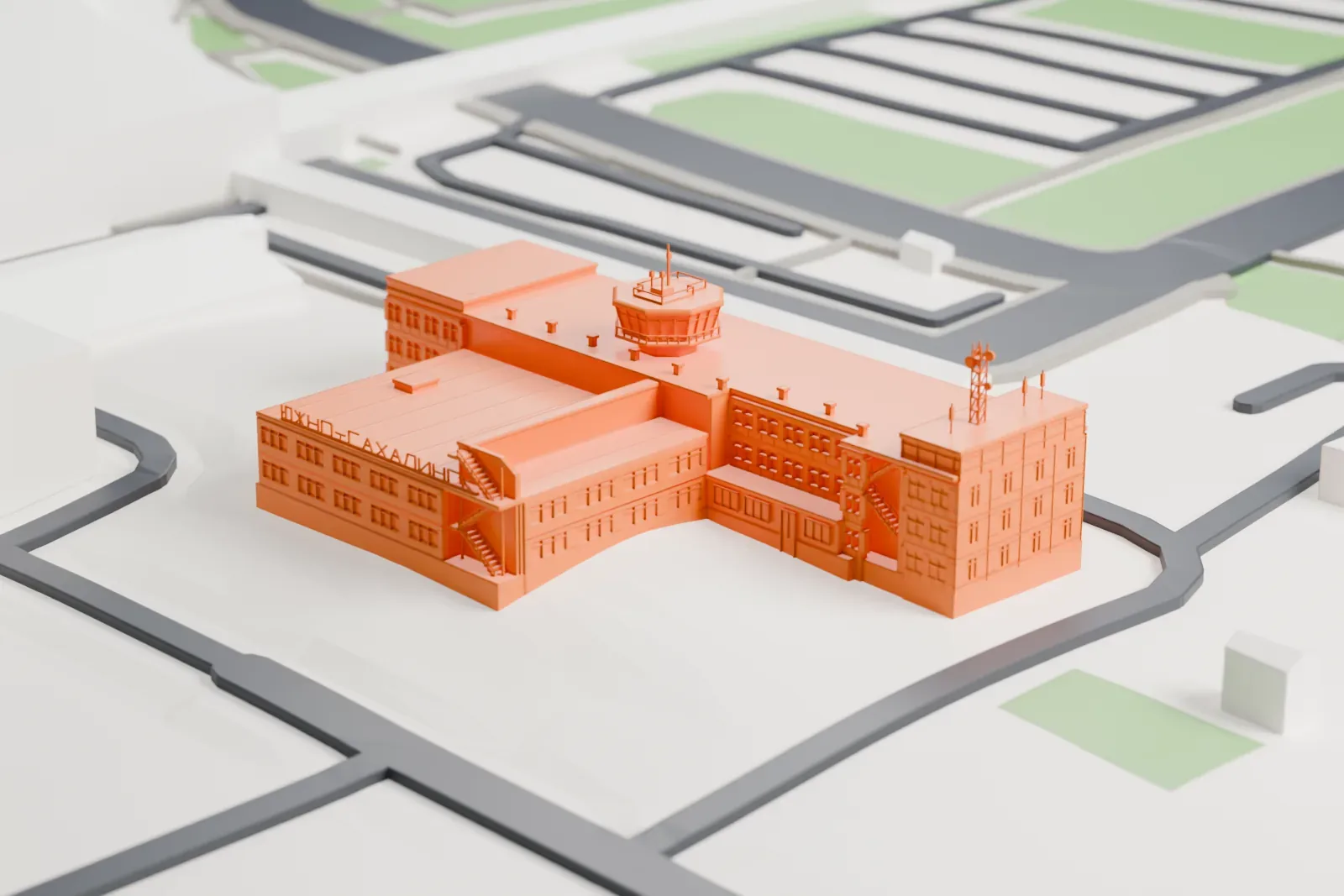 A white 3D print of the Yuzhno-Sakhalinsk Airport Old Terminal, a long terminal building with a glazed entrance and a flared control cab on the roof, among surrounding airport buildings.