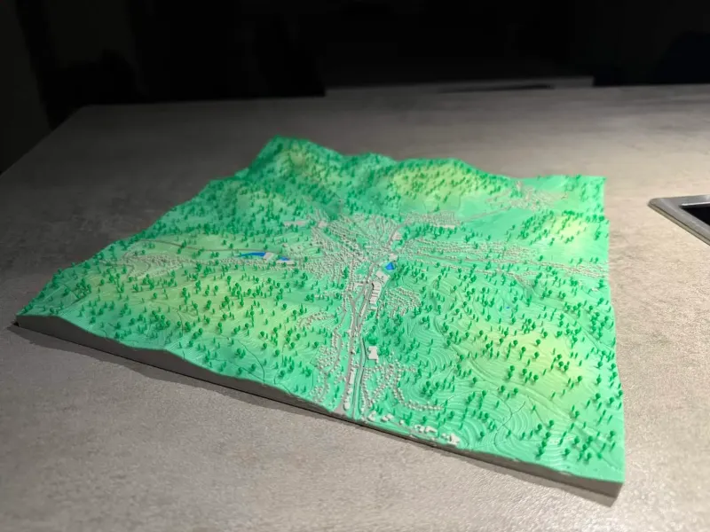 3D printed green terrain relief of forested hills and valleys.
