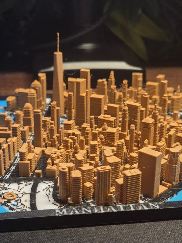 Framed 3D printed map of a downtown with tall buildings and the place name on the frame.